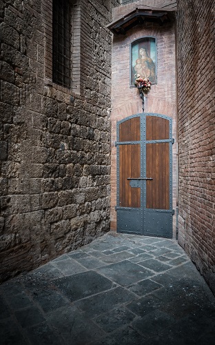Narrow medieval entrance with virgin Mary mural in Siena, Tuscany, Italy